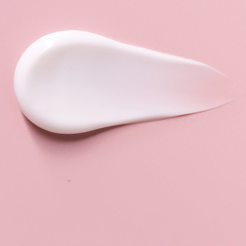 Texture de crème blanche en un coup de pinceau sur fond rose clair.